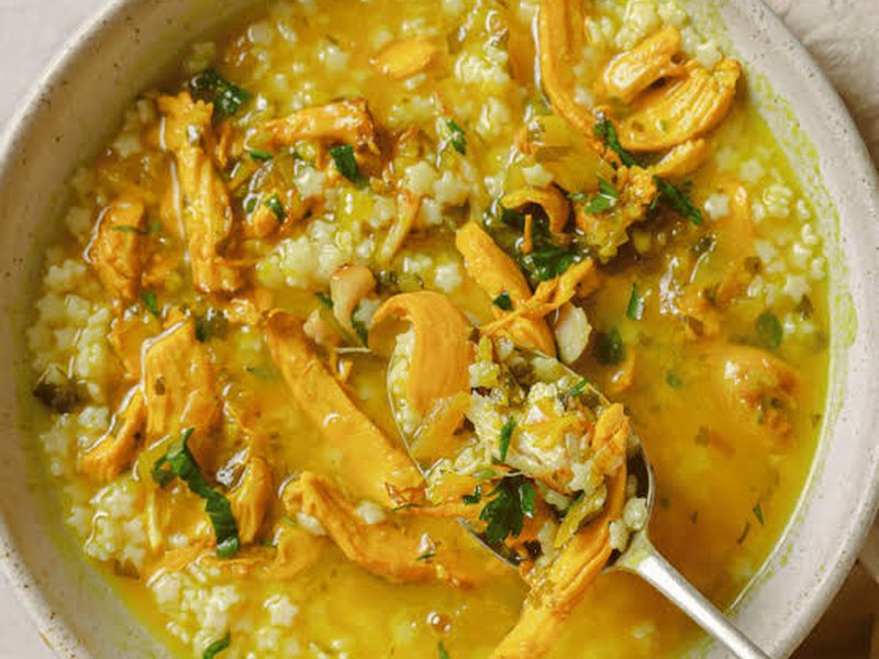 A golden bowl of chicken soup with tiny pastina pasta, shredded chicken and fresh herbs.